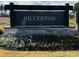 Silverton community sign with flower beds and a glimpse of a home in the background, showcasing the neighborhood's entrance at 196 Silverton Dr, Dacula, GA 30019