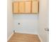 Small laundry room with light wood floors and natural wood cabinets at 4785 Beaver Rd, Loganville, GA 30052