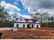 New construction shows an inviting white farmhouse-style home with a dark roof and black trim amid a wooded landscape at 490 Benson Meadows Dr, Dallas, GA 30157
