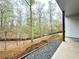View of the backyard from the covered porch, overlooking a wooded area with a wooden fence and rock detail at 305 Red Gate Ln, Canton, GA 30115