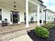 Inviting front porch featuring brick flooring, rocking chairs, and a charming exterior lighting fixture at 305 Red Gate Ln, Canton, GA 30115