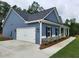 Attached garage with a concrete driveway next to a stylish blue home with stone accents at 476 Benson Meadows Dr, Dallas, GA 30157