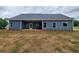 Rear exterior of the home features blue siding, a covered patio, and a level yard. Multiple windows provide natural light at 476 Benson Meadows Dr, Dallas, GA 30157