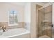 Bright bathroom featuring a soaking tub with tile surround and a shower at 7554 Roseberry Way, Lithonia, GA 30038