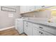 Bright laundry room featuring white cabinets, wooden floors, and stainless steel appliances including a modern washer and dryer at 20 Tuscany Dr, Mansfield, GA 30055