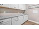 Bright laundry room with white cabinets, granite counters, and wood floors at 20 Tuscany Dr, Mansfield, GA 30055