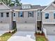 Modern townhome with a gray brick facade, complemented by a neutral gray garage door and manicured landscaping at 1387 Fern Ridge Ct # 33, Norcross, GA 30093