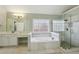 Bright bathroom featuring a soaking tub, glass shower, white cabinets, vanity, and tile floor at 5615 Toccoa Dr, Douglasville, GA 30135