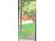 View through glass door of a private backyard with lush grass, a wooden fence, and mature trees at 6802 Potomac, Fairburn, GA 30213