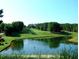 Scenic view of a lush green golf course with a serene pond and mature trees on a clear day at 4385 Hickory Flat Hwy, Canton, GA 30115