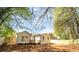 Open backyard featuring a new fence and mature trees surrounding a charming white home and deck at 716 Sunfield Nw Dr, Lilburn, GA 30047