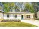 Charming one-story home with a well-manicured lawn, fresh flowers, and a blue front door at 716 Sunfield Nw Dr, Lilburn, GA 30047
