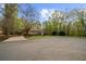 Exterior view of the home featuring a long driveway, large front yard, and partial forest view at 420 Longs Peak, Johns Creek, GA 30022