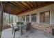 Covered outdoor patio with stone detail featuring a dining table with four chairs and wood beam ceiling at 420 Longs Peak, Johns Creek, GA 30022
