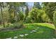 Lush backyard with a stone walkway, surrounded by green grass and mature trees for a peaceful, private oasis at 2628 Rivers Nw Rd, Atlanta, GA 30305