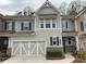 Charming townhome featuring a two-car garage, gray siding, stone accents, and beautiful landscaping at 2460 Laurel Gate Ln, Cumming, GA 30040