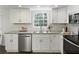 Bright kitchen features white cabinets, stainless steel appliances, granite countertops, and a window overlooking the backyard at 520 Willeo Rd, Roswell, GA 30075
