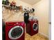 Functional laundry room with shelving and red, front-loading washer and dryer at 859 Pownal Ln, Hampton, GA 30228