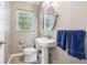 Cozy bathroom with a pedestal sink, framed mirror, and natural light from the window at 2434 Skyland Ne Trl, Brookhaven, GA 30319