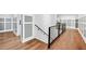 Hallway with hardwood flooring, black metal railing and modern door frames, creating an open and airy transition between rooms at 109 Owens Mill Pl, Canton, GA 30115
