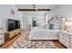 Bright main bedroom with hardwood floors, king bed, beamed ceiling, and a large television at 109 Owens Mill Pl, Canton, GA 30115