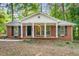 Charming one-story brick home featuring a classic front porch and manicured lawn surrounded by mature trees at 2612 Clairmont Ne Rd, Atlanta, GA 30329