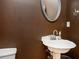 Powder room featuring a vintage-style pedestal sink, round mirror, and chocolate brown wall at 4743 Longcourt Se Dr, Atlanta, GA 30339