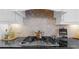 Close up of a stylish stovetop with stone tile backsplash and modern range hood at 722 Laurel Canyon Pkwy, Canton, GA 30114
