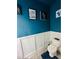 Comfortable powder room with a toilet, decorative wall paneling, striking blue walls, and unique artwork at 3132 Meadowstone Sw Ln, Atlanta, GA 30331