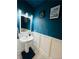 Stylish powder room with a pedestal sink, modern fixtures, decorative wall paneling, and unique artwork at 3132 Meadowstone Sw Ln, Atlanta, GA 30331