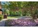A view of a backyard with a lush green lawn covered in pink petals, perfect for relaxation at 5162 Charlemagne Sw Way, Lilburn, GA 30047