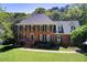 Beautiful two-story brick home with green shutters and a well-manicured lawn and mature trees at 5162 Charlemagne Sw Way, Lilburn, GA 30047