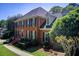 Side view of a brick two-story home featuring manicured shrubs and a walkway at 5162 Charlemagne Sw Way, Lilburn, GA 30047
