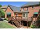Exterior elevation of a brick home, featuring a backyard deck with stairs at 5162 Charlemagne Sw Way, Lilburn, GA 30047