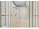 A shower stall featuring patterned wallpaper, a glass door, a shower head and gold towel rack at 5162 Charlemagne Sw Way, Lilburn, GA 30047