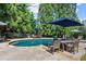 Backyard pool and patio area, complete with table, chairs, umbrellas, and mature trees at 2314 Edgemere Lake Cir, Marietta, GA 30062