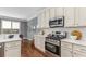 Well-lit kitchen with stainless steel appliances, white cabinets, and hardwood floors at 1324 Cambridge Ave. Sw, Atlanta, GA 30344