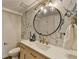 Stylish bathroom with a modern round mirror, gold fixtures and a marble accent wall at 1450 Cedarhurst Dr, Dunwoody, GA 30338