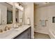 Modern bathroom with double sinks, marble countertop, gold fixtures, and bathtub at 1450 Cedarhurst Dr, Dunwoody, GA 30338