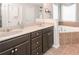 Bright bathroom featuring a double vanity, soaking tub, and neutral tile at 5111 Olive Branch Cir, Powder Springs, GA 30127