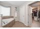 Bathroom with soaking tub and tiled surround, next to a walk-in closet at 5111 Olive Branch Cir, Powder Springs, GA 30127