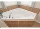 Corner bathtub with tile surround and chrome fixtures under a window at 5111 Olive Branch Cir, Powder Springs, GA 30127