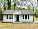 Charming single-story home with a light blue exterior, black door, and well-manicured lawn at 517 Whitley Dr, Forest Park, GA 30297