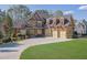 A detailed view of the home's exterior, featuring brick and stone accents, and a well-manicured lawn at 6925 Lighthouse Point, Cumming, GA 30041