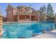 Beautiful in-ground pool with lush landscaping and backyard view of the brick home at 6925 Lighthouse Point, Cumming, GA 30041