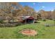 View of barn surrounded by green grass and budding trees at 300 Smith Ave, Bowdon, GA 30108