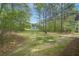 Lush backyard with mature trees and green grass, with a view of the house at 164 Edison Dr, Stockbridge, GA 30281