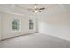 Spacious primary bedroom with tray ceiling, ceiling fan, and two windows letting in natural light at 164 Edison Dr, Stockbridge, GA 30281