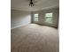 Bright primary bedroom featuring plush carpeting, two windows, and a ceiling fan at 10918 Gallier St, Alpharetta, GA 30022