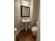 Chic half bathroom with pedestal sink, toilet, and wood-look floors at 10918 Gallier St, Alpharetta, GA 30022